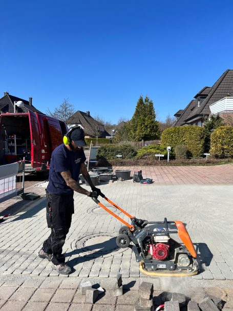 Handwerker verdichtet eine frisch verlegte Pflasterfläche in Goslar mit einer Rüttelplatte für eine stabile und gleichmäßige Oberfläche.