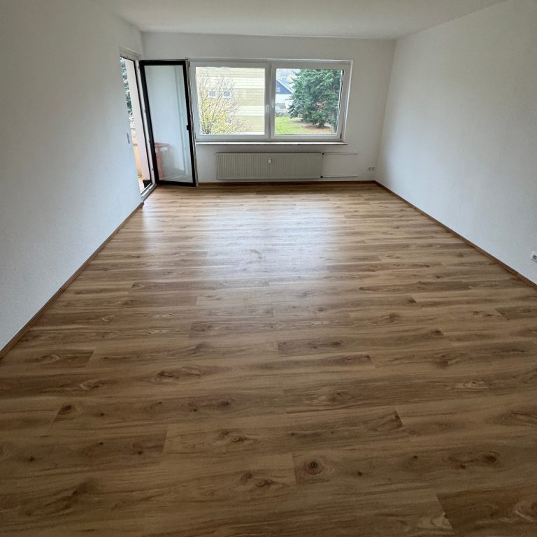 Renoviertes Wohnzimmer mit neu verlegtem Vinylboden und frisch gestrichenen Wänden für eine moderne Raumwirkung.